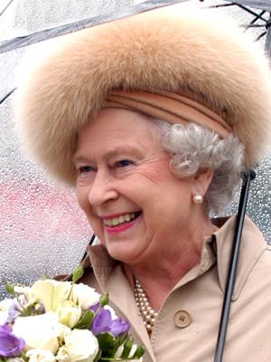 Photo of Queen in the rain wearing fur hat holding flowers and an umbrella. Item # GR2012.0472-168.0011